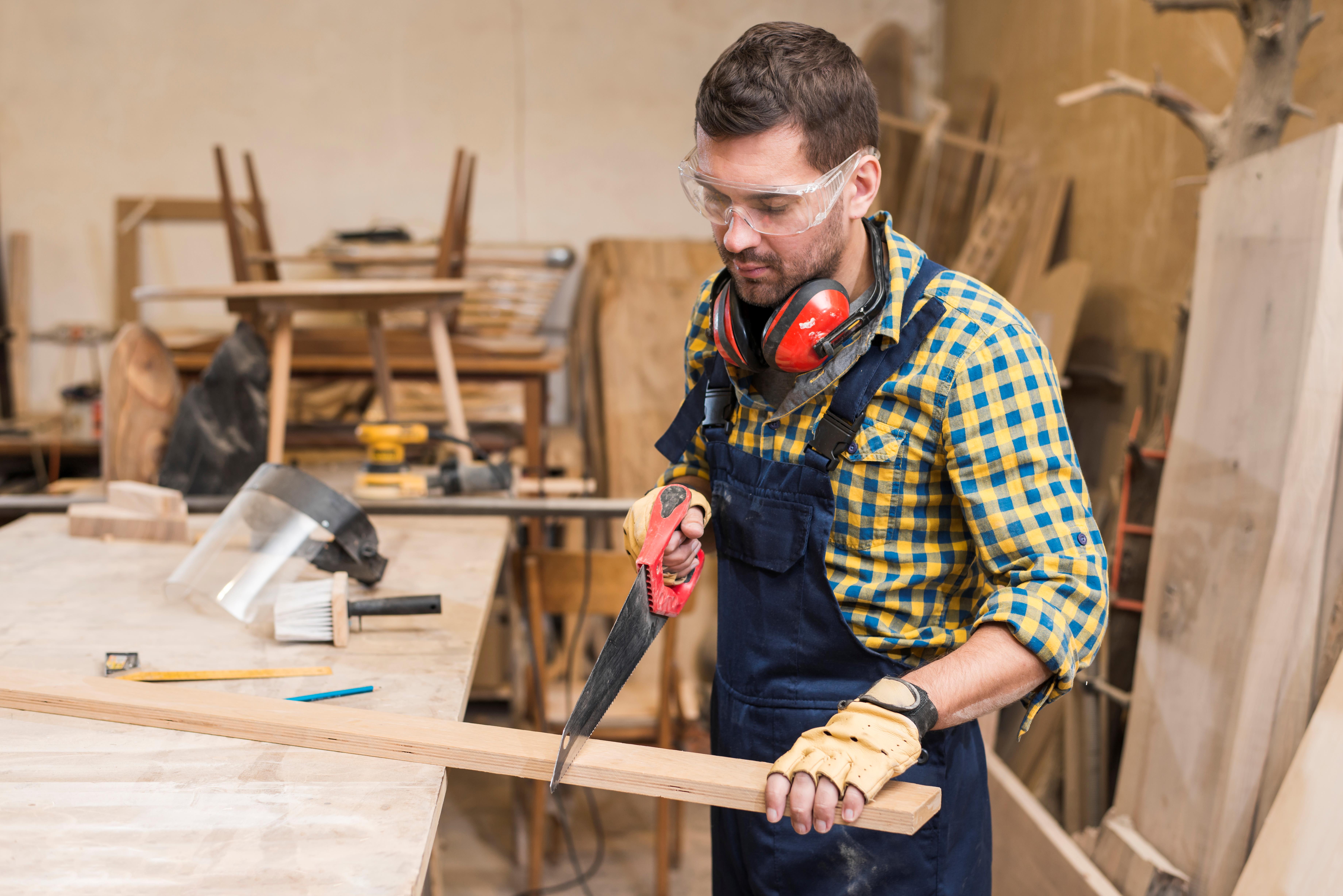 close-up-handyman-sawing-long-wooden-plank