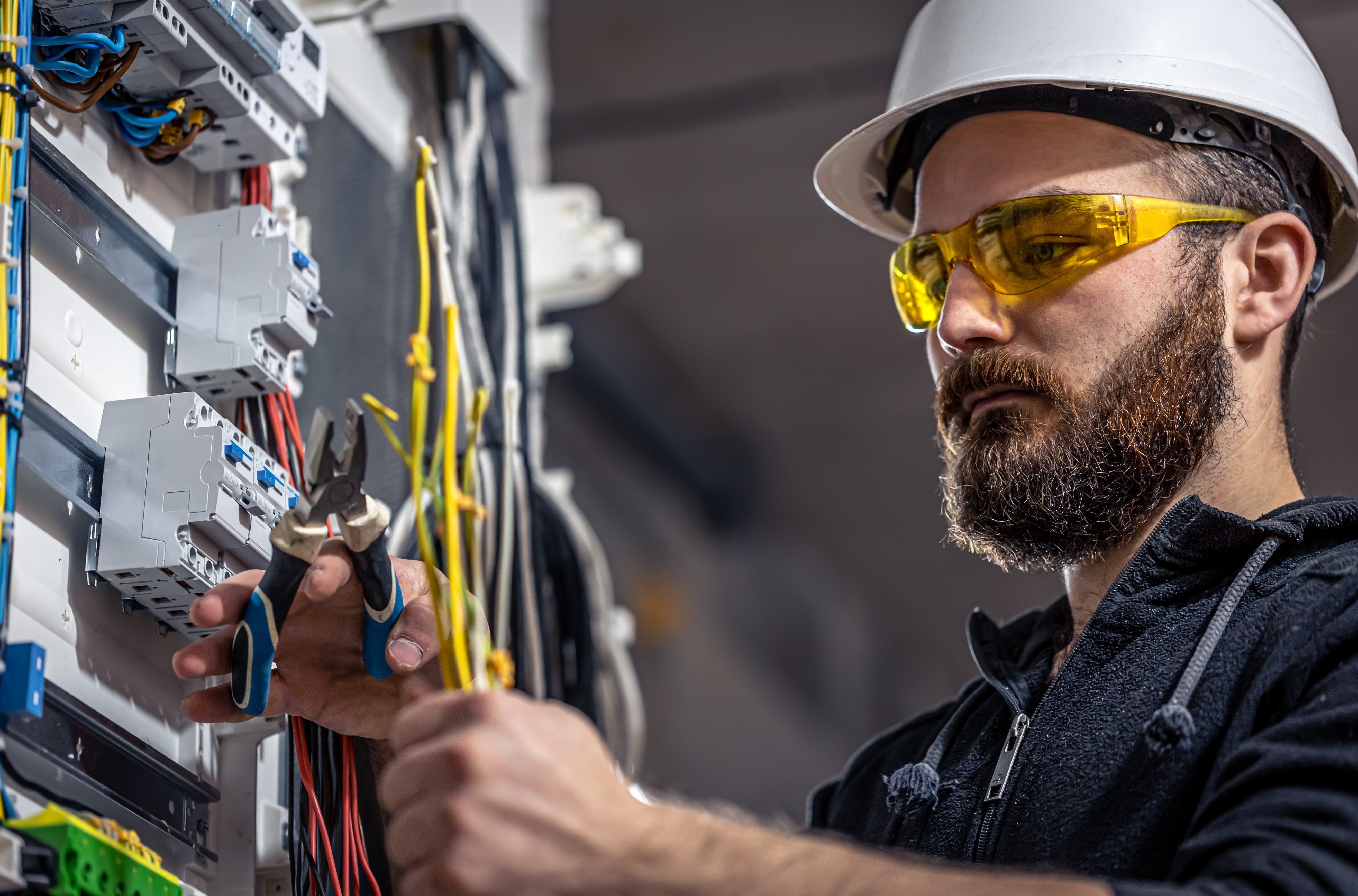 male-electrician-works-switchboard-with-electrical-connecting-cable